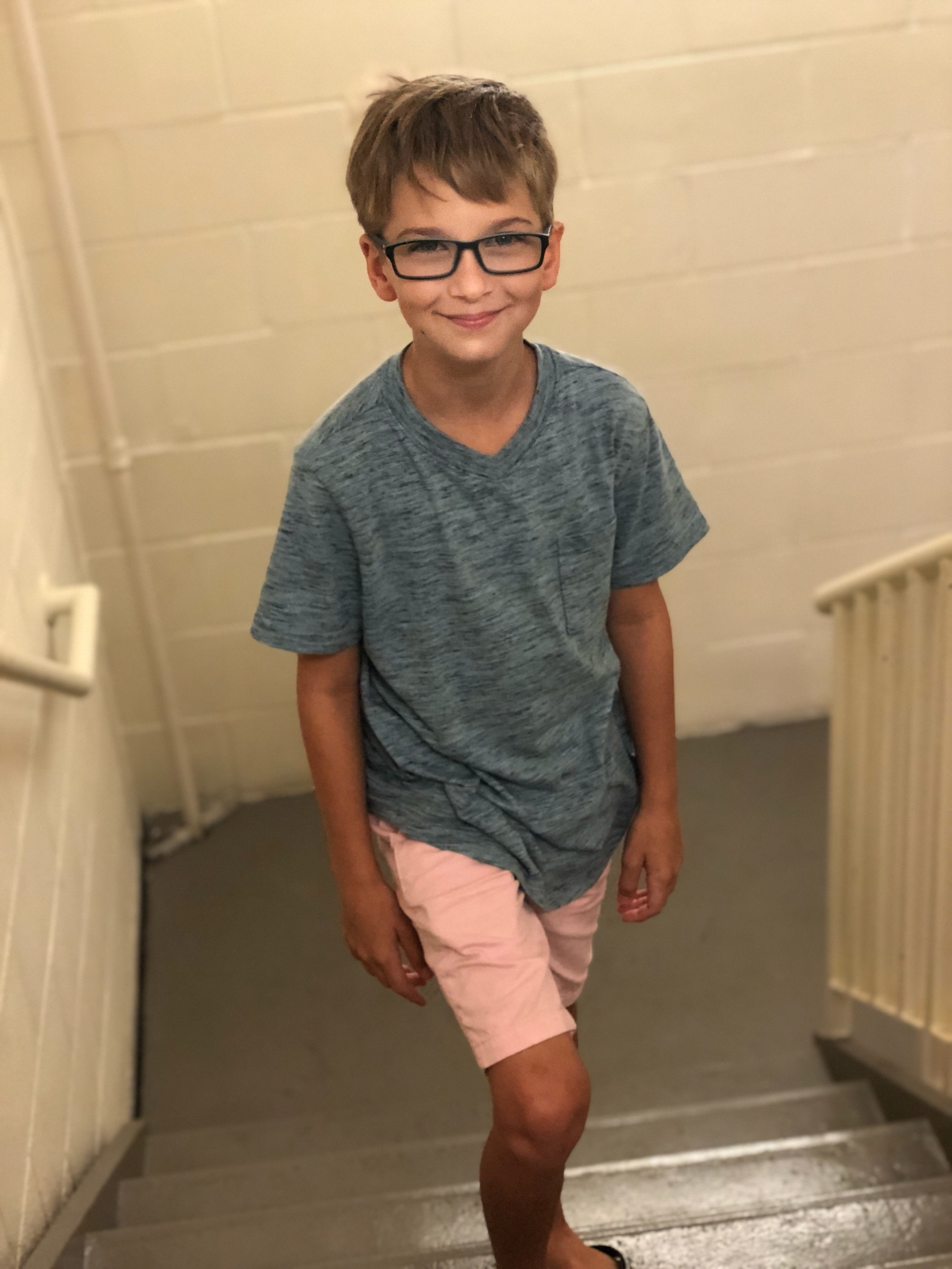 pediatric patient wearing glasses smiling standing on stairs