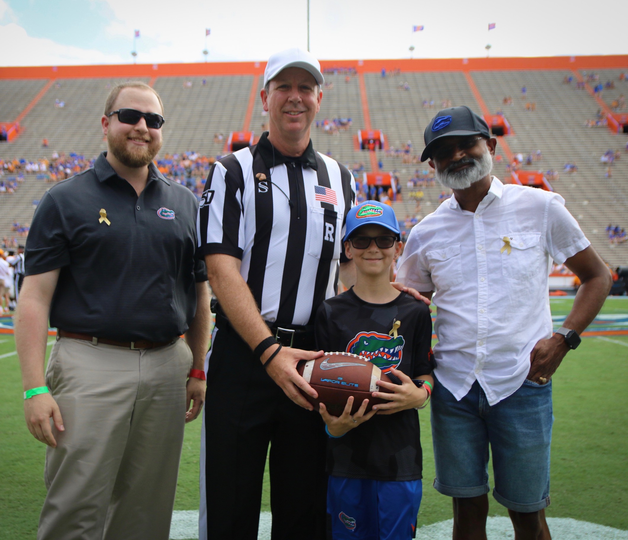 Mikah with the game ball, his doctor and a referee in The Swamp